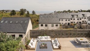 Une terrasse sur le toit, avec des sièges en plein air et une vue sur la mer.