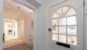 A white door with a glass panel and a window, leading to a hallway with a patterned rug and a ceiling light fixture. - Seascape - 3 Bedrooms (North Berwick)