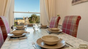A dining table set for four with a view of the city and sea. - Seascape - 3 Bedrooms (North Berwick)
