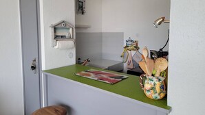 A compact kitchen with a green countertop, a wooden stool, a decorative pitcher, and a small shelf with kitchen utensils. - Directly on the beach for this charming one-bedroom flat with private parking - 4OND28 (SAINT CYPRIEN PLAGE)
