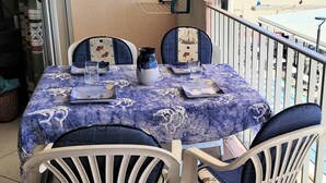 A balcony with a table set for two, featuring a blue patterned tablecloth, white chairs, and a vase. - Directly on the beach for this charming one-bedroom flat with private parking - 4OND28 (SAINT CYPRIEN PLAGE)