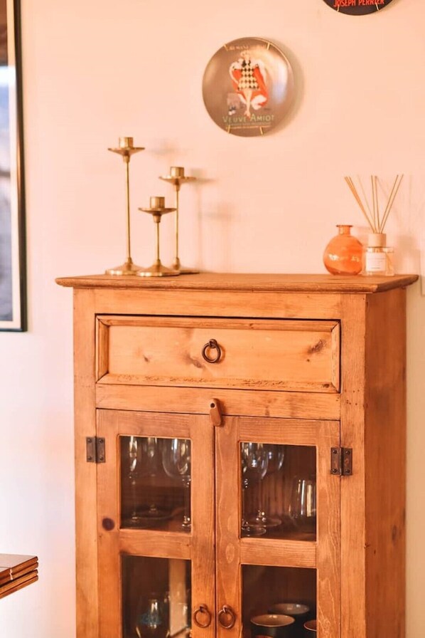 A wooden cabinet with two glass doors, a small drawer, and a round wall decoration above it.