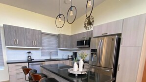A modern kitchen with a central island, bar stools, stainless steel appliances, and pendant lighting. - CASA COCO-CORAL Premium 3 Master @ Casa Linda (Sosúa)