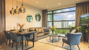 Ein modernes Wohnzimmer mit einer Couch, einem Esstisch, Stühlen und einem Fernseher.