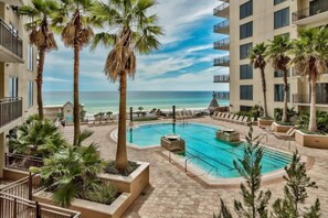 A hotel pool area with palm trees, a clear sky, and a view of the ocean. - Origin 504 | Ocean view & Pool view | Sleeps 5 (Panama City Beach)