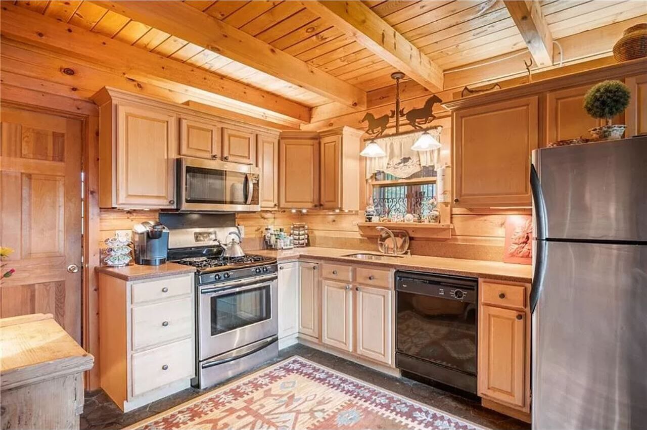 A kitchen with wooden cabinets, stainless steel appliances, and a patterned rug.