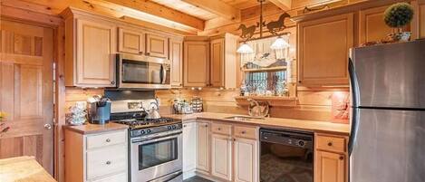 A kitchen with wooden cabinets, stainless steel appliances, and a patterned rug.