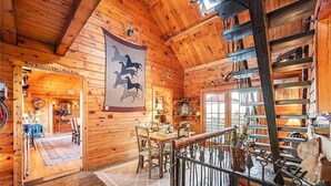 A wooden cabin interior with a dining area, a staircase, and a display of antlers. - Rustic/Modern Lodge near French Lick - Groups and Families (West Baden Springs)