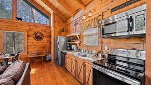 A cabin-style kitchen with wooden walls, a large stove, and a refrigerator. - Free Dollywood Tix/Pool/Arcade/Spacious/HotTub/ (Sevierville)
