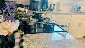 A kitchen with granite countertops, a stove, a coffee maker, and a sink.