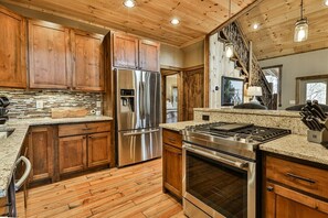 A kitchen with wooden cabinets, stainless steel appliances, a granite countertop, and a wooden floor. - Doc & Molly`s | Cherry Log, Ga (Cherry Log)