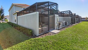 A modern house with a glass-enclosed porch and air conditioning units.