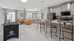 A modern living room with a foosball table, a sofa, and a dining area with chairs.
