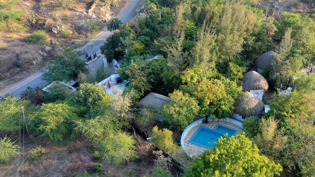An aerial view of a property with a swimming pool, a road, and surrounding vegetation. - Nature Retreat Cottages Jaisamand Udaipur  (Udaipur)