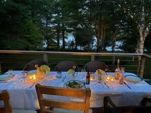 Un espace de restauration en plein air avec des tables pour deux personnes, chacune agrémentée d’une nappe blanche, de bougies et de verres.