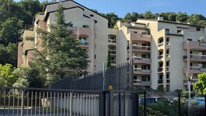 A gated residential complex with multiple buildings, a gravel driveway, and large rocks in the foreground.