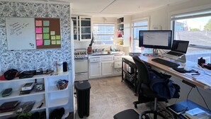 A compact, modern kitchen with white cabinets, a built-in oven, and a sink. There is a computer desk with a laptop and a desktop monitor. - WFH surfer dream spot in Morro Bay - Looking for a March & April booking (Morro Bay)