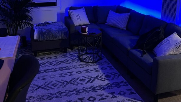 A modern living room with a dark-colored sofa, a patterned rug, and a small side table. - WFH surfer dream spot in Morro Bay - Looking for a March & April booking (Morro Bay)