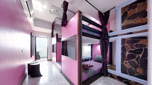 A room with pink walls, a stone accent wall, a bunk bed, a flat-screen TV, and a large window with curtains. - Kerton Hostel (Koh Samui)