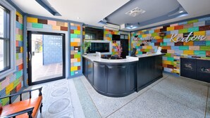 A modern kitchen with a colorful mosaic wall, a central island, and a reception desk with a sign reading "Weekend Bungalow". - Kerton Hostel (Koh Samui)