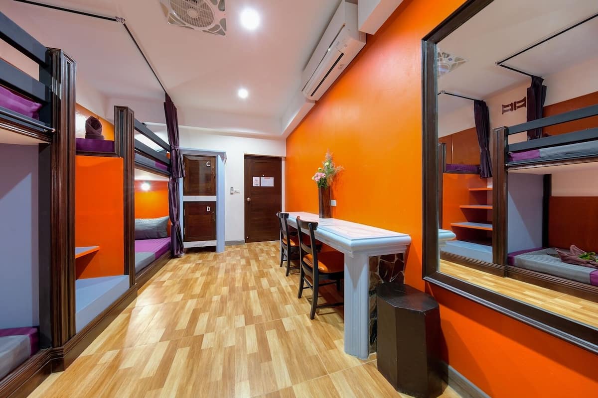 A room with bunk beds, a small table, and a mirror.