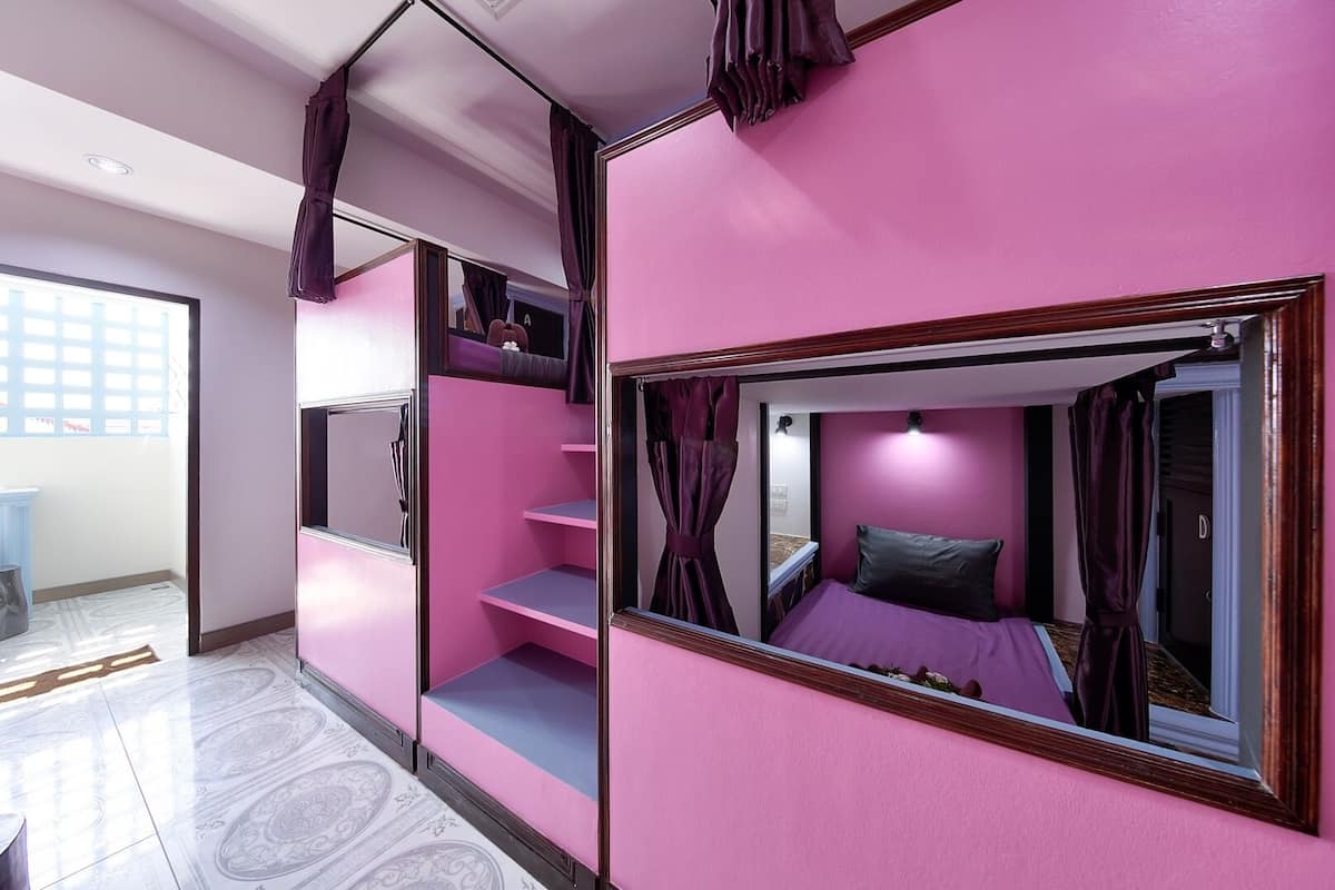 A pink-themed bedroom with a bed, a mirror, and a wardrobe.