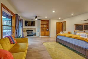 Una camera da letto con un letto, un divano, un camino e una ventola a soffitto.