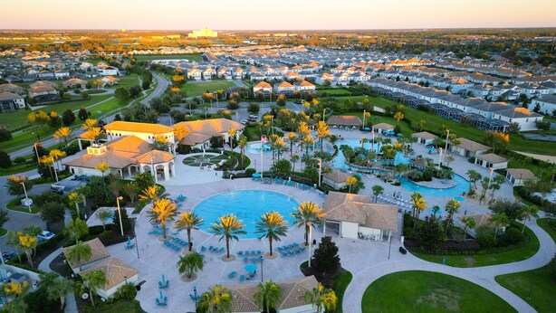 Zona residencial con una amplia piscina rodeada de palmeras y un club social.