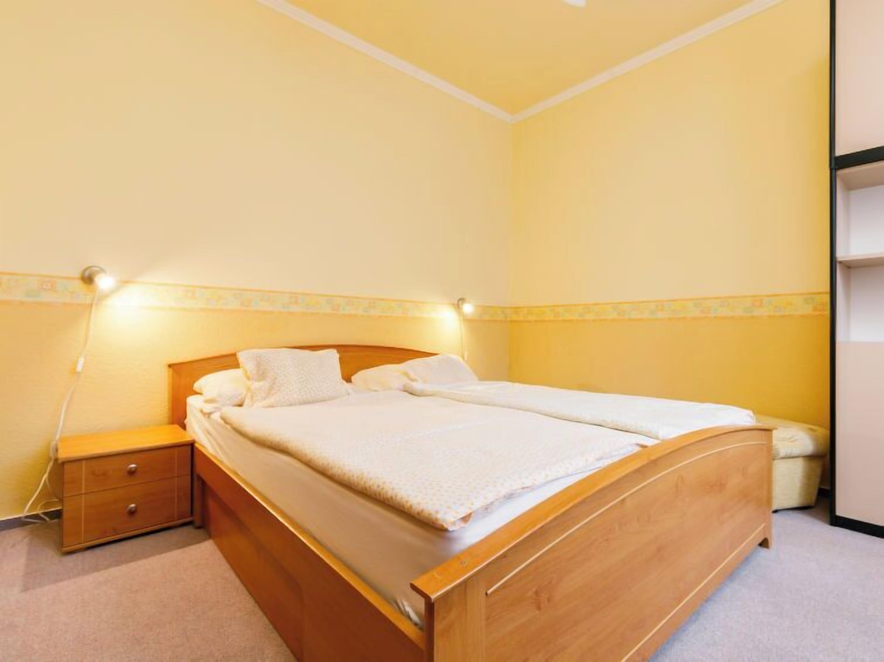 A single-bed room with a wooden headboard, a bedside table, and a nightstand.