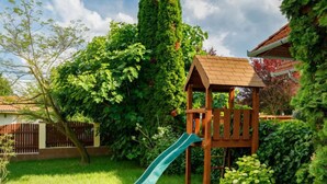 A wooden playhouse with a slide in a lush backyard. - Vacation home Edina by Interhome (Balatonszarszo)