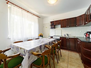 Un comedor con una mesa dispuesta para seis personas, rodeada de sillas de madera con cojines verdes.
