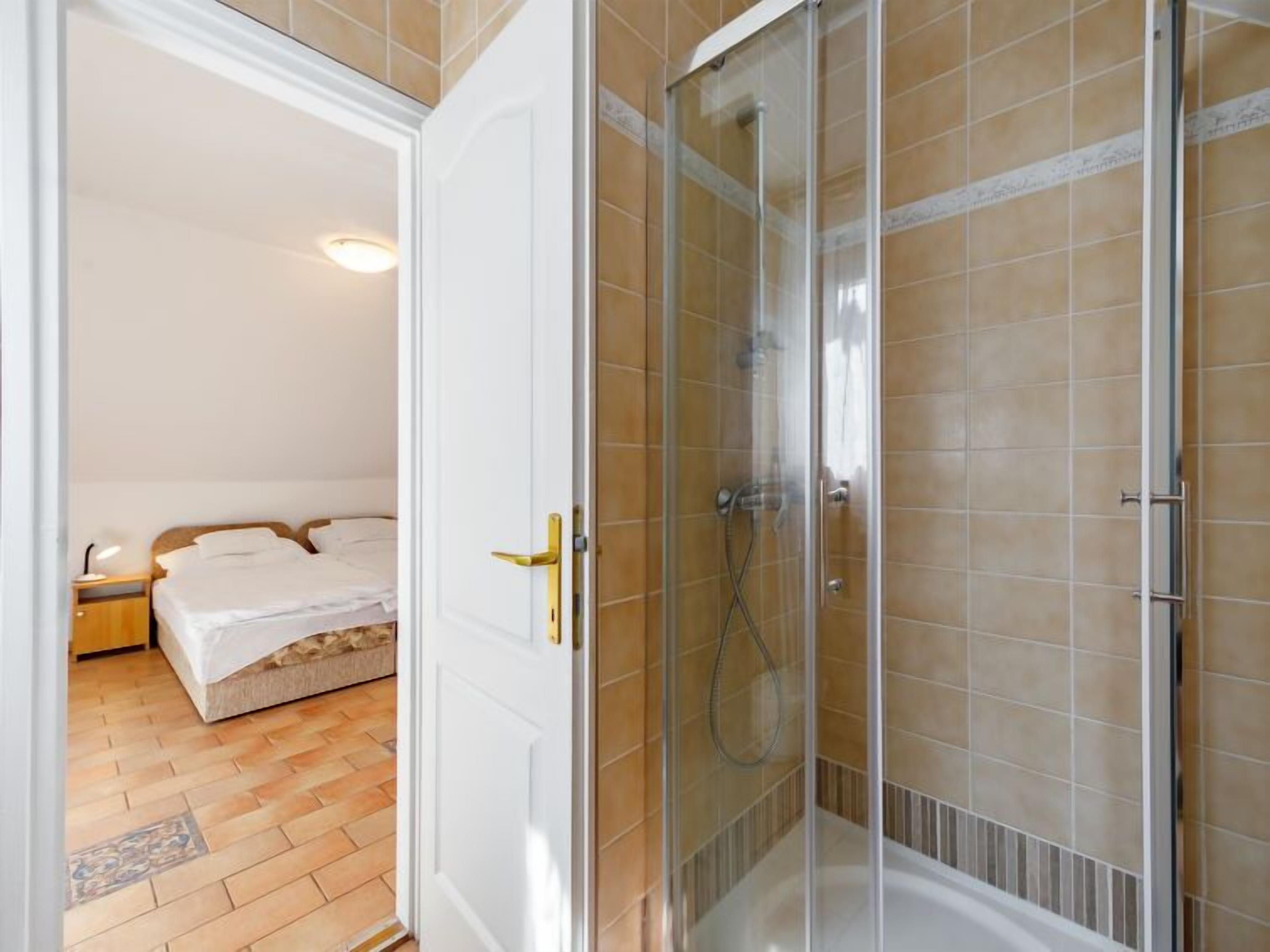 Een hotelkamer met een douche, een bed en een klein nachtkastje.