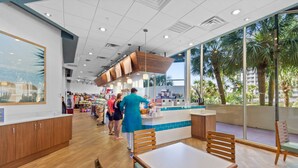 A restaurant interior with wooden flooring, a counter with a blue tiled backsplash, and large windows offering a view of palm trees. - $150 activities - E-gift card when you book - Southern Ocean View with Gorgeous Sunsets | RP1906-2 (Myrtle Beach)