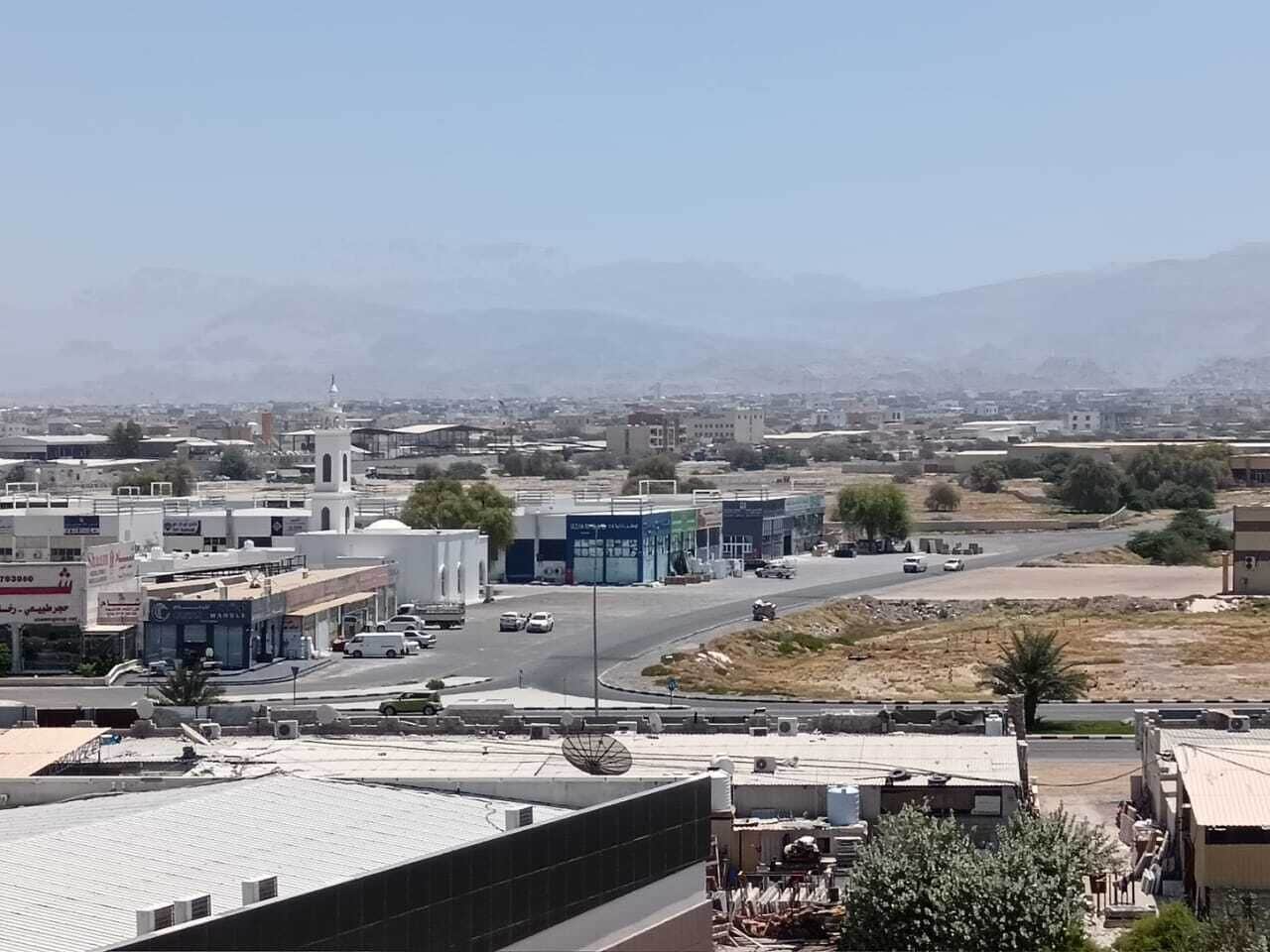 A cityscape with buildings, roads, and a distant mountain range.