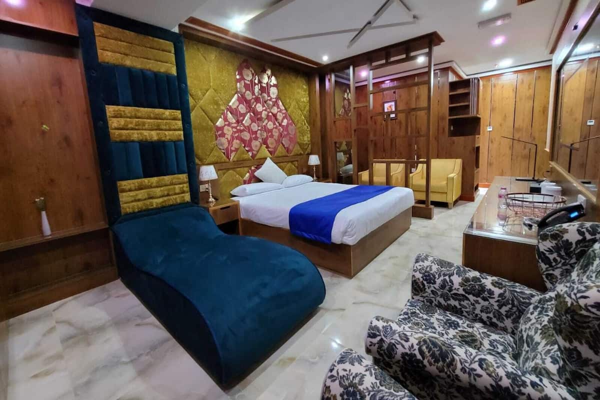 Una camera d'albergo con un letto, un divano, una scrivania e una televisione.