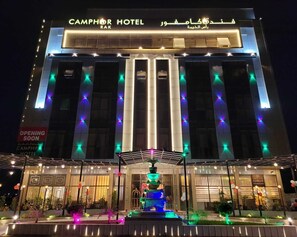 The exterior of the Camphor Hotel with illuminated vertical columns and a central fountain. - Camphor Hotel (Ras Al Khaimah)