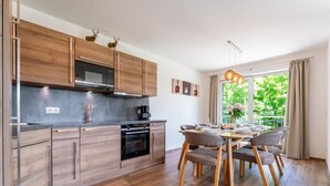 Une cuisine moderne avec des meubles en bois, un four encastré et un coin repas comprenant une table et des chaises.