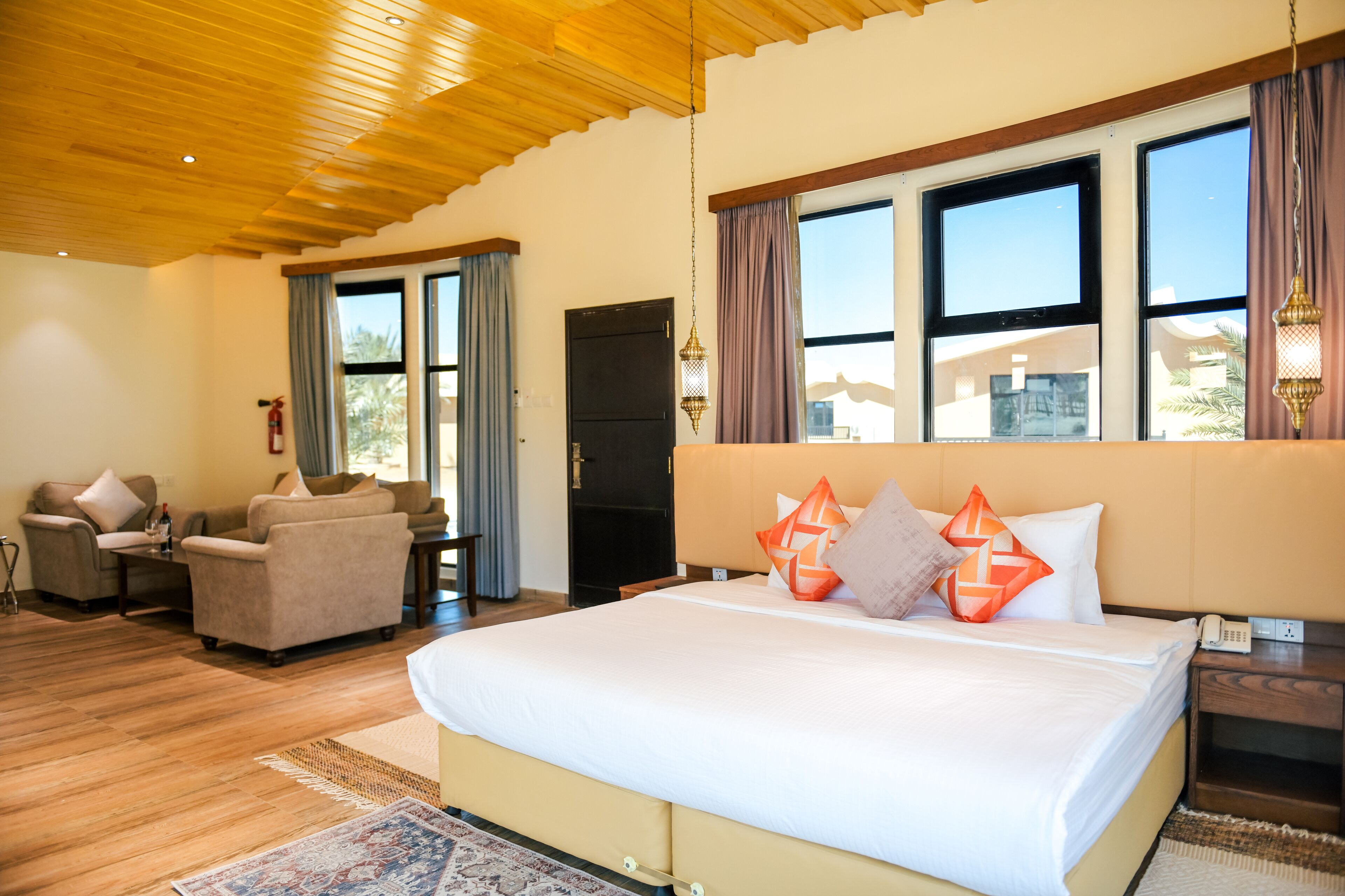 Um quarto espaçoso com uma cama grande, uma área de estar com dois sofás e teto de madeira.