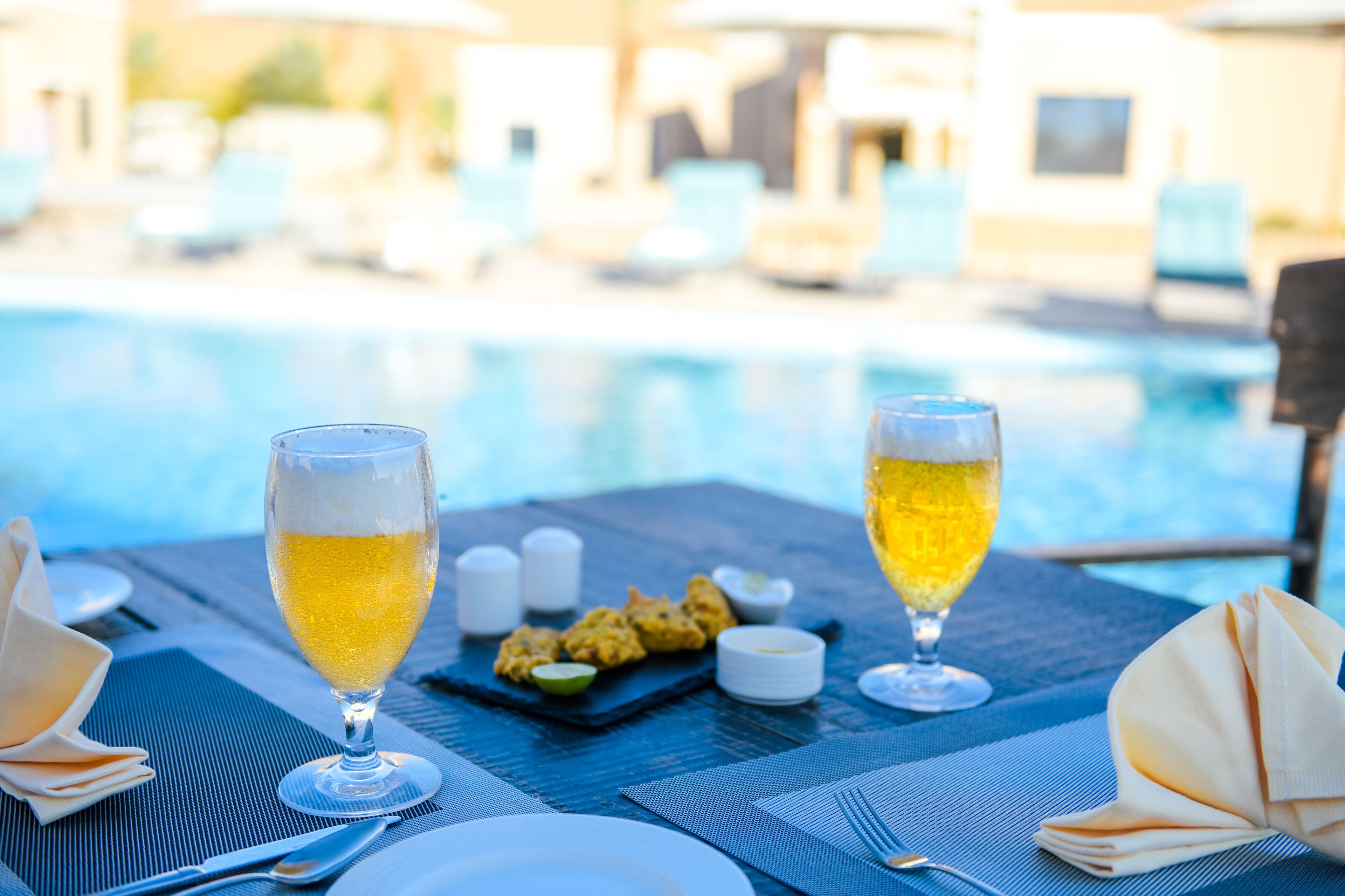 Una mesa con dos copas de champán, un plato pequeño de aperitivos y saleros y pimenteros.