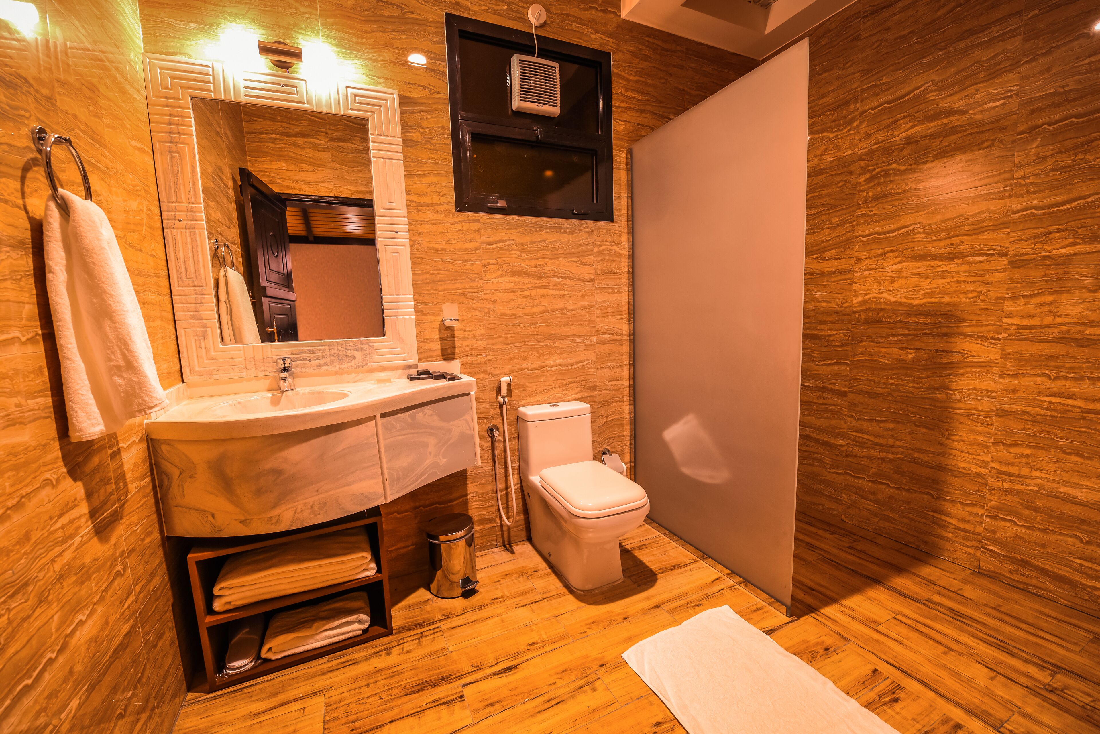 Ein Badezimmer mit Holzboden, Waschbecken, Toilette und Spiegel.