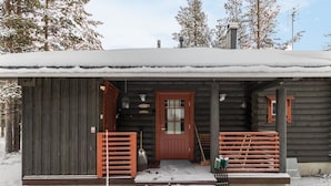 Une cabane en rondins avec une porte en bois, un porche avec un banc et un toit recouvert de neige.