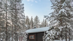 Une cabane en rondins entourée d’arbres couverts de neige.