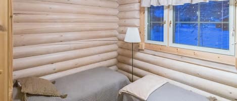 Une chambre de style rustique avec deux lits, une fenêtre avec des stores et une lampe.