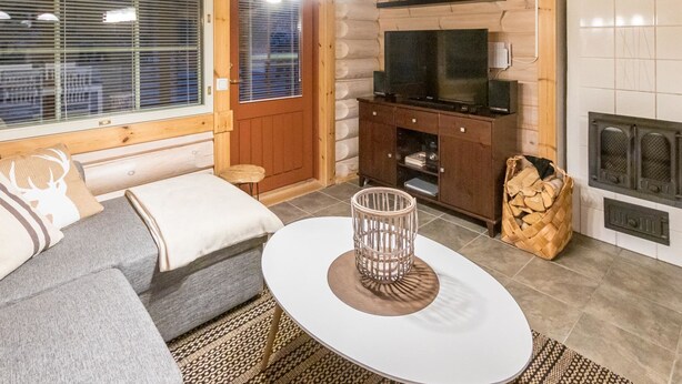 Une pièce confortable, aménagée comme un chalet, avec un canapé, une petite table ronde, un téléviseur et une cheminée.
