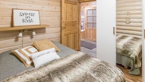 Une chambre confortable dans un chalet en rondins, avec un lit, une pancarte indiquant « Accordez-vous du repos » et une vue sur une autre pièce.