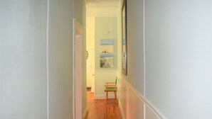 A narrow hallway with wooden flooring, a green chair, and a painting on the wall. - OCEAN BLOCK Downtown Rehoboth Beach 2BR Condo Sleeps 6 (Rehoboth Beach)