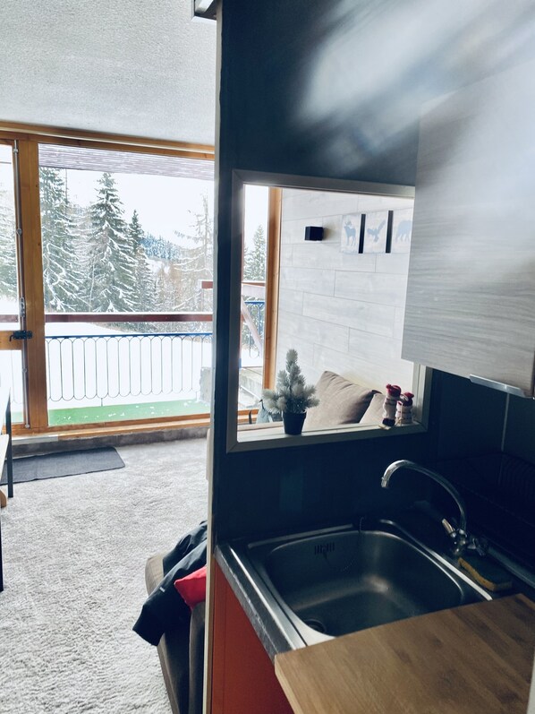A modern kitchen with a large window, a sink, and a view of a snowy landscape.