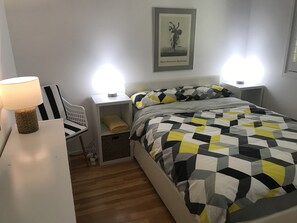 Cozy retreat with a geometric-patterned bed, framed artwork, and a comfortable chair.