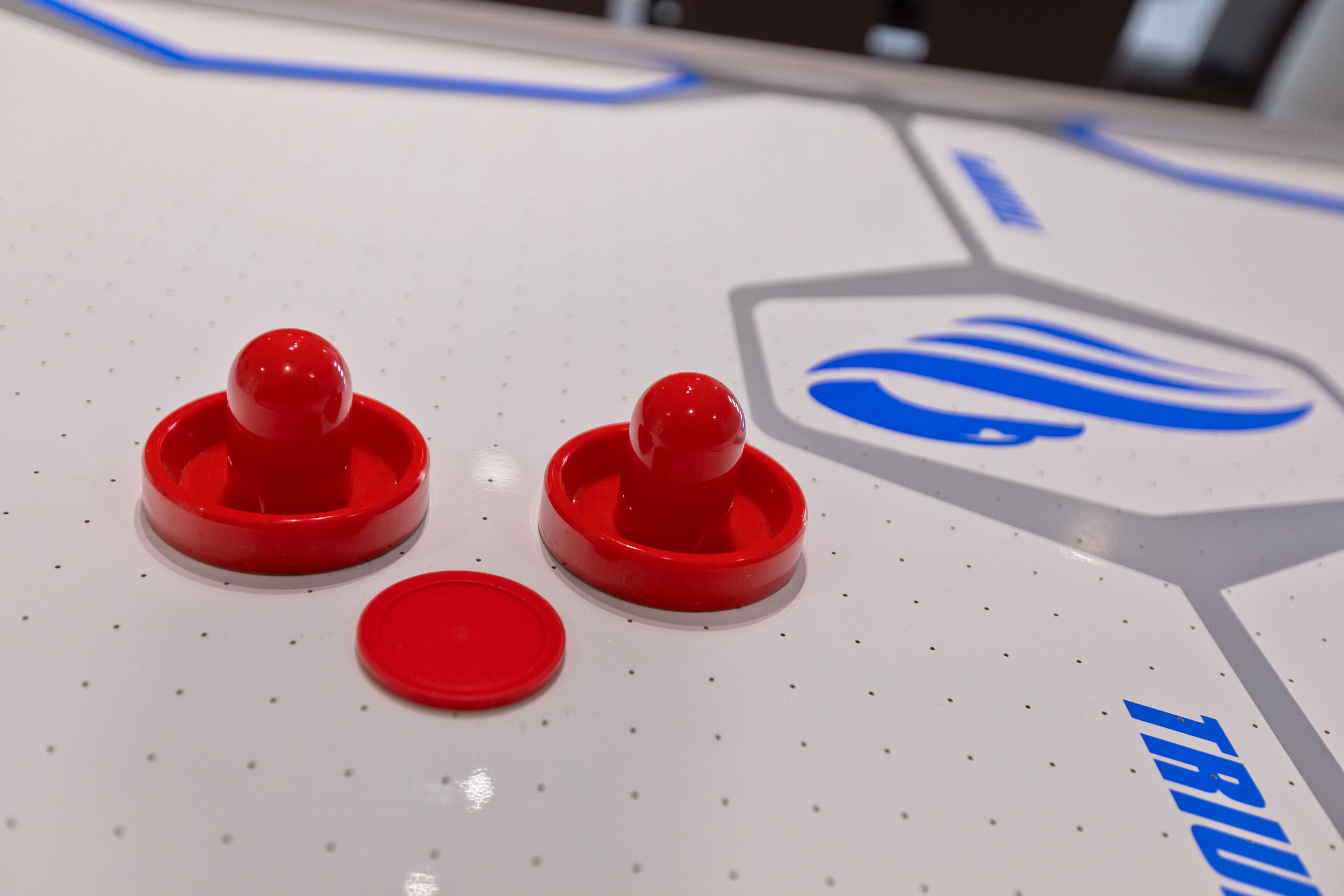A close-up of a white table with red objects and a blue logo.