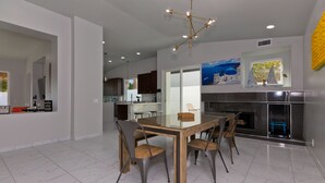 Une cuisine moderne avec une table à manger en verre, des chaises foncées et un îlot central.